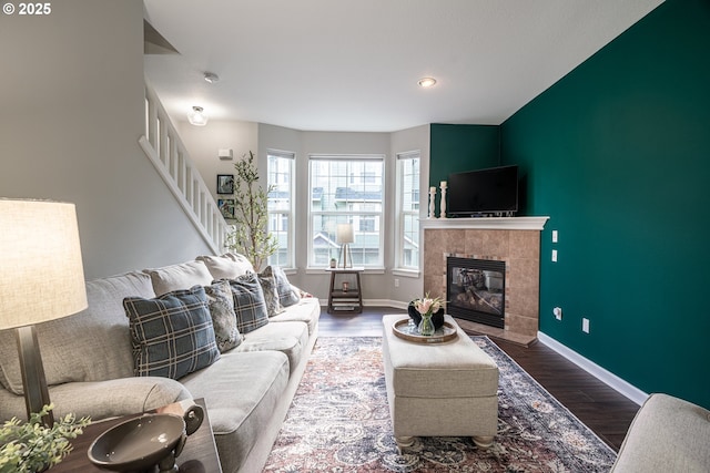 living room featuring recessed lighting, wood finished floors, baseboards, stairs, and a tiled fireplace