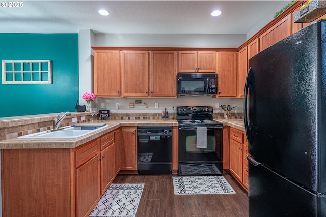 kitchen with dark wood-style floors, light countertops, a sink, a peninsula, and black appliances