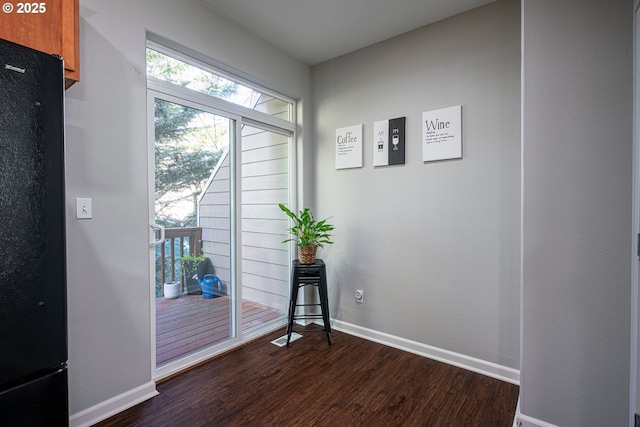 doorway with baseboards and dark wood finished floors