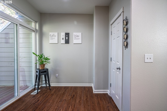 hallway featuring baseboards and dark wood-type flooring