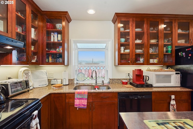 kitchen with a toaster, glass insert cabinets, light stone counters, black appliances, and a sink