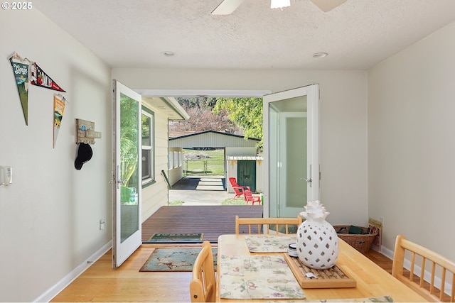 doorway to outside with a ceiling fan, a textured ceiling, baseboards, and wood finished floors