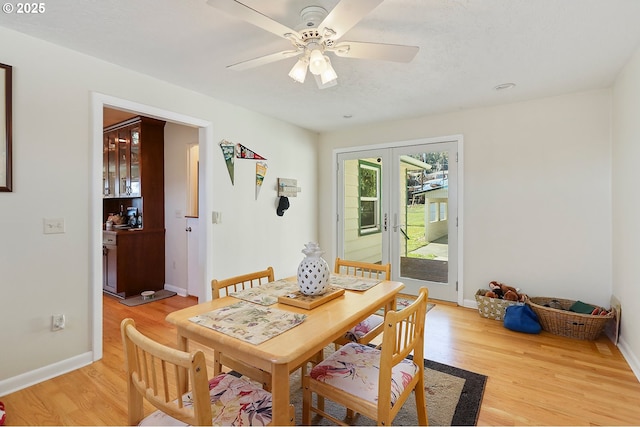 dining space featuring french doors, light wood finished floors, a ceiling fan, and baseboards