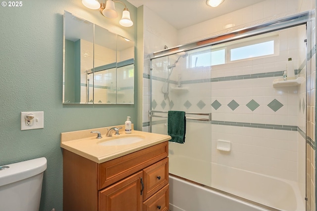 bathroom with a textured wall, combined bath / shower with glass door, vanity, and toilet