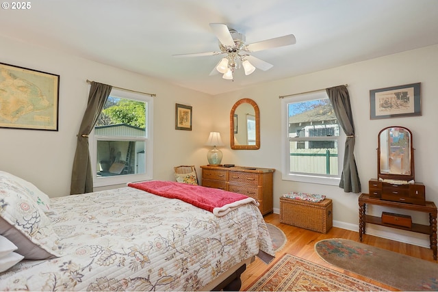 bedroom with light wood finished floors, ceiling fan, and baseboards