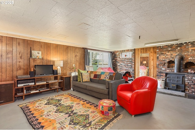 living area with concrete flooring, a wood stove, and wooden walls