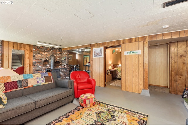 living room with a wood stove, visible vents, concrete floors, and wooden walls