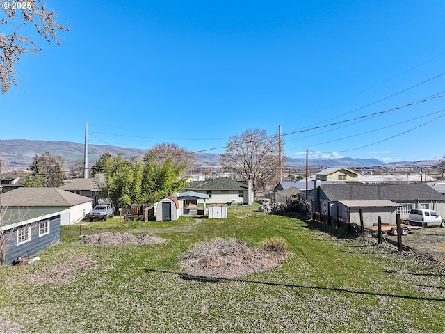 view of yard with an outbuilding, a mountain view, a residential view, and a shed