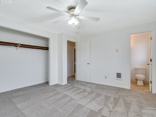 unfurnished bedroom featuring baseboards, carpet, a closet, a textured ceiling, and a ceiling fan