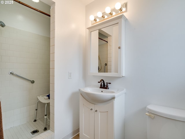 bathroom with tiled shower, toilet, and vanity