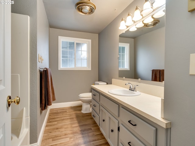 bathroom with vanity, toilet, wood finished floors, and baseboards