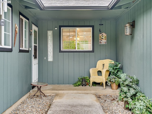 entrance to property with a porch and a shingled roof