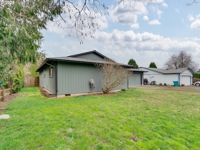 view of side of home featuring a lawn, an attached garage, driveway, and fence