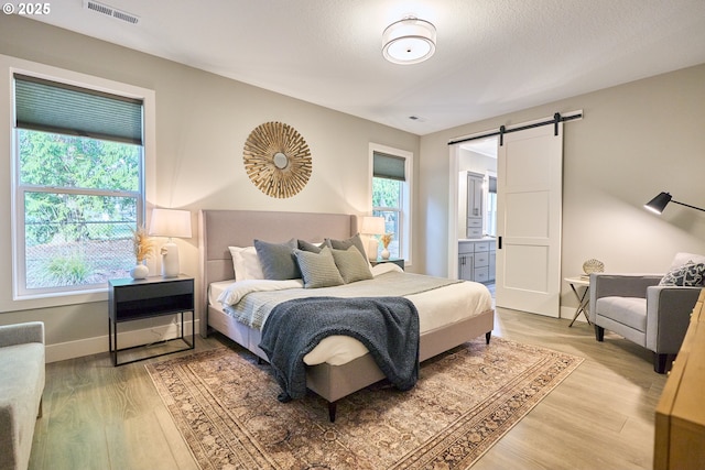 1718 SE 40th St, Brush Prairie, WA 98606 - bedroom featuring a barn door, light wood-style floors, and ensuite bathroom