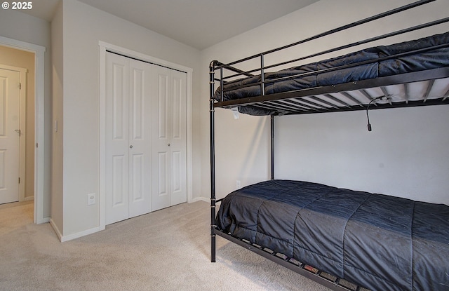 bedroom with light carpet, a closet, and baseboards
