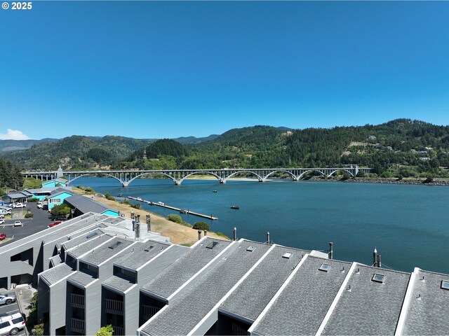94304 Wedderburn Loop Unit 445, Gold Beach, OR 97444 - water view with a notable bridge, a mountain backdrop, and a forest