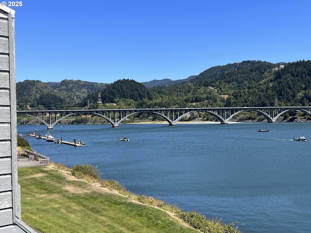 94304 Wedderburn Loop Unit 445, Gold Beach, OR 97444 - water view with a notable bridge, a heavily wooded area, and a mountainous background