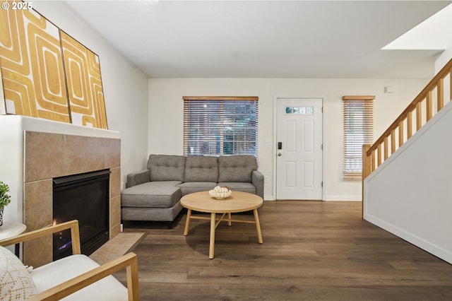 living area featuring a wealth of natural light, wood finished floors, a tiled fireplace, and baseboards