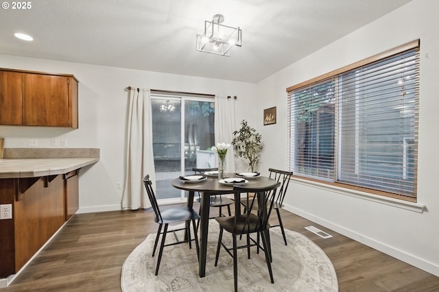 dining room with visible vents, baseboards, and dark wood-style floors