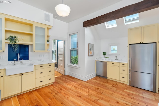 2664 NW Thurman St, Portland, OR 97210 - kitchen featuring stainless steel appliances, a sink, a skylight, cream cabinets, and lofted ceiling