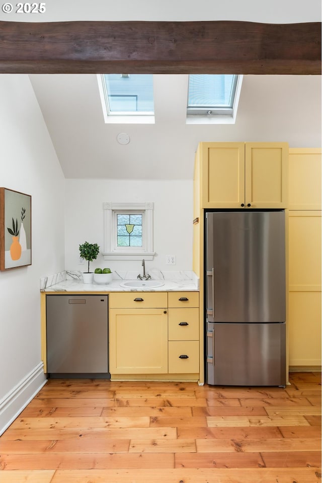 2664 NW Thurman St, Portland, OR 97210 - kitchen with stainless steel appliances, a skylight, a sink, light countertops, and lofted ceiling