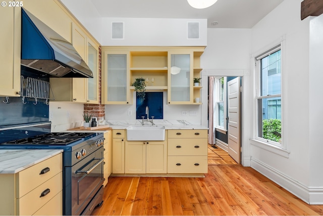 2664 NW Thurman St, Portland, OR 97210 - kitchen featuring stainless steel range with gas cooktop, a sink, ventilation hood, light wood-style floors, and cream cabinetry