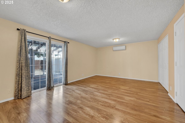 523 65th St, Springfield, OR 97478 - empty room featuring a textured ceiling, light wood finished floors, an AC wall unit, and baseboards