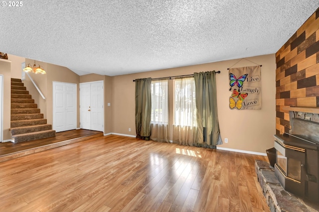 523 65th St, Springfield, OR 97478 - unfurnished living room featuring a wood stove, a textured ceiling, stairway, baseboards, and wood finished floors