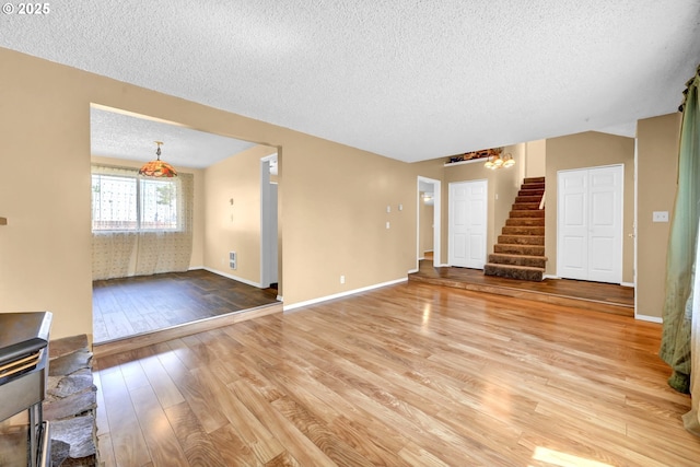 523 65th St, Springfield, OR 97478 - unfurnished living room featuring a textured ceiling, stairs, light wood finished floors, a chandelier, and baseboards