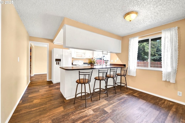 523 65th St, Springfield, OR 97478 - kitchen featuring white appliances, dark wood finished floors, white cabinets, dark countertops, and a peninsula