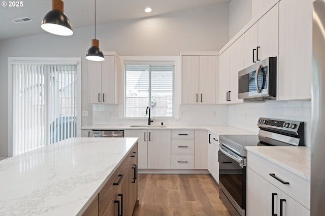 2417 NE 2nd Ct, Battle Ground, WA 98604 - kitchen featuring stainless steel appliances, a sink, light wood finished floors, backsplash, and light stone countertops