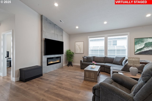 2417 NE 2nd Ct, Battle Ground, WA 98604 - living room featuring recessed lighting, baseboards, wood finished floors, a tile fireplace, and lofted ceiling
