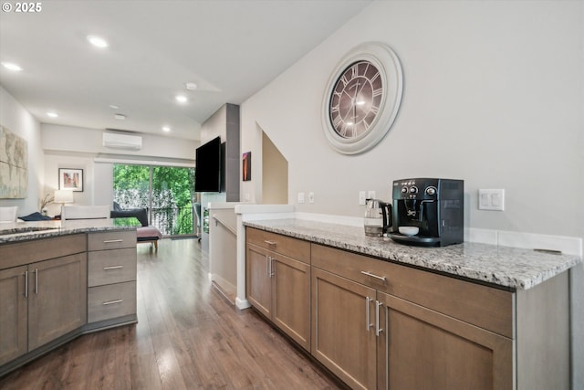 kitchen featuring dark wood-style flooring, open floor plan, light stone countertops, an AC wall unit, and recessed lighting