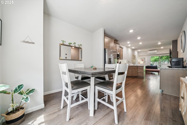 dining room featuring wood finished floors, recessed lighting, baseboards, and an AC wall unit