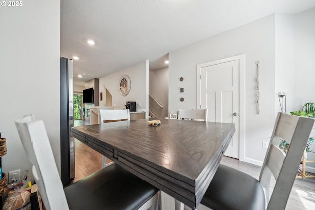 dining area featuring light wood-style flooring, recessed lighting, stairs, and baseboards