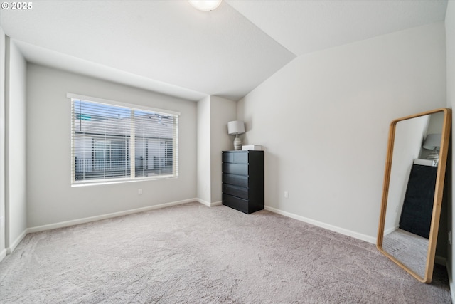unfurnished bedroom featuring carpet, vaulted ceiling, and baseboards