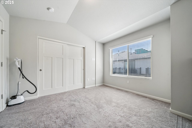 unfurnished bedroom with carpet flooring, lofted ceiling, baseboards, and a closet