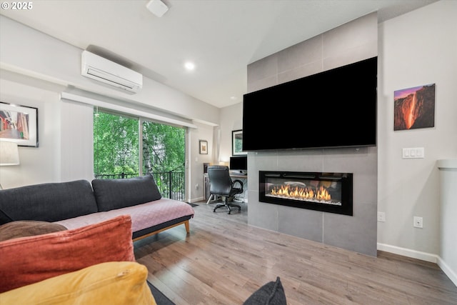 living room featuring an AC wall unit, wood finished floors, a fireplace, baseboards, and recessed lighting
