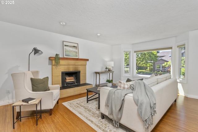 13555 SW Hiteon Ct, Beaverton, OR 97008 - living room featuring wood finished floors, a tile fireplace, a textured ceiling, and recessed lighting