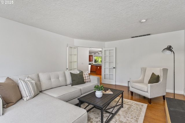 13555 SW Hiteon Ct, Beaverton, OR 97008 - living area with light wood-style floors, a textured ceiling, and baseboards