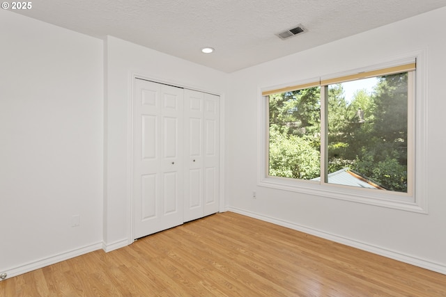 13555 SW Hiteon Ct, Beaverton, OR 97008 - unfurnished bedroom with light wood-style floors, recessed lighting, a textured ceiling, and a closet