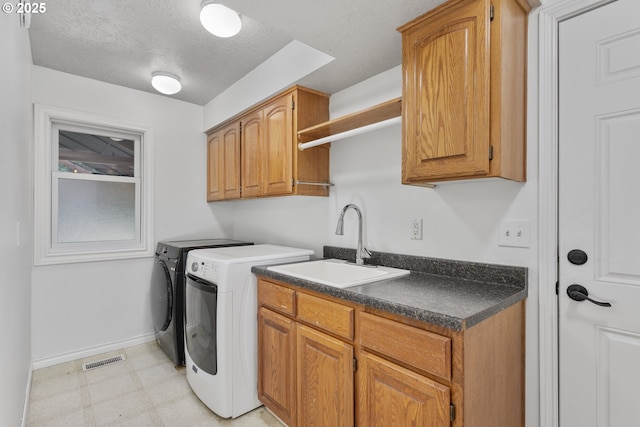 13555 SW Hiteon Ct, Beaverton, OR 97008 - laundry room with washing machine and clothes dryer, cabinet space, a textured ceiling, and light flooring