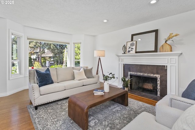 13555 SW Hiteon Ct, Beaverton, OR 97008 - living area featuring a tile fireplace, wood finished floors, plenty of natural light, baseboards, and a textured ceiling