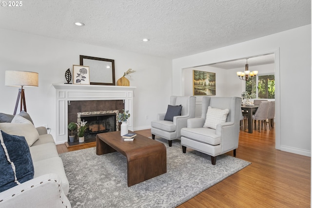 13555 SW Hiteon Ct, Beaverton, OR 97008 - living room featuring wood finished floors, a chandelier, a textured ceiling, a fireplace, and recessed lighting