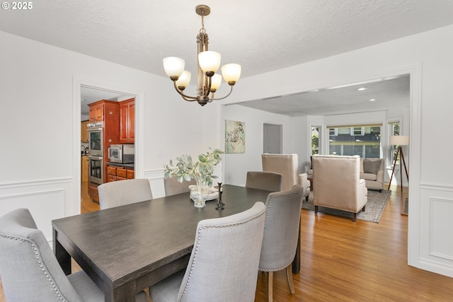 13555 SW Hiteon Ct, Beaverton, OR 97008 - dining room with a chandelier, light wood-style flooring, and a textured ceiling