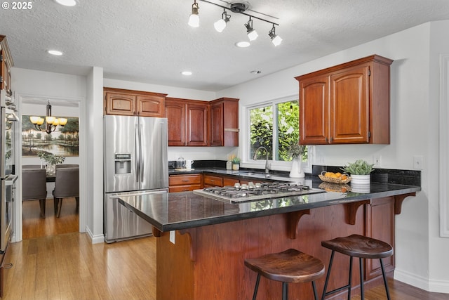 13555 SW Hiteon Ct, Beaverton, OR 97008 - kitchen featuring appliances with stainless steel finishes, a peninsula, light wood finished floors, a textured ceiling, and recessed lighting