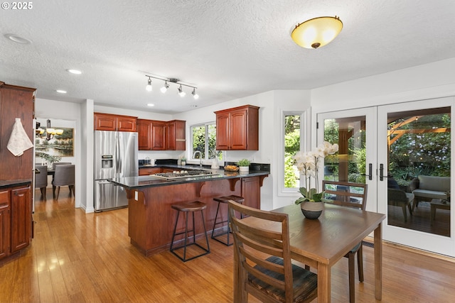 13555 SW Hiteon Ct, Beaverton, OR 97008 - kitchen featuring stainless steel appliances, a peninsula, dark countertops, light wood-type flooring, and a textured ceiling