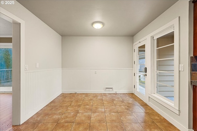 empty room with a wainscoted wall and light tile patterned flooring