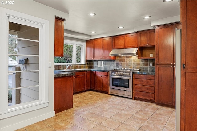 kitchen with tasteful backsplash, brown cabinets, high end stainless steel range, under cabinet range hood, and a sink