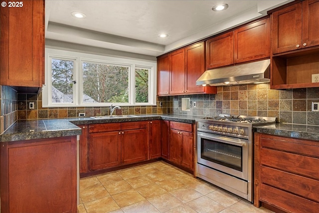 kitchen featuring backsplash, light tile patterned flooring, a sink, high end stove, and under cabinet range hood